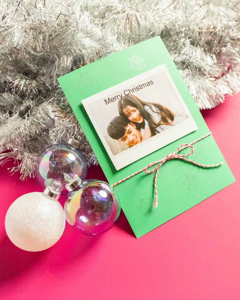 instax™ print card laying on tinsel next to baubles